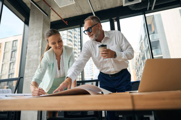 istock Joyous woman and her office collegue discussing paperwork on table 1443082401