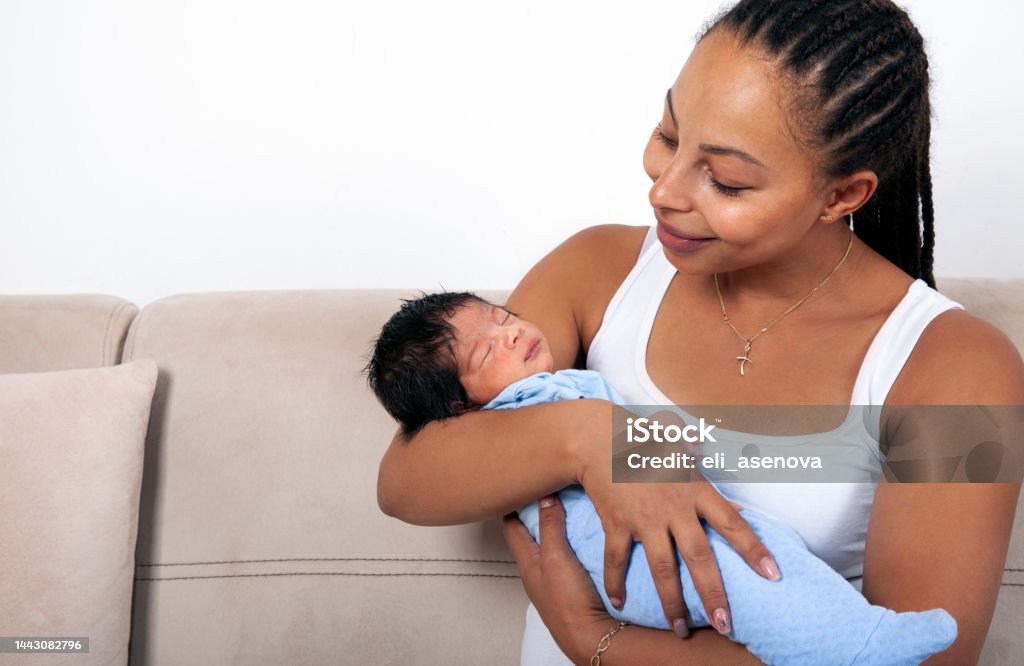 Beautiful African American mother holds newborn baby in the living room 0-1 Months Stock Photo