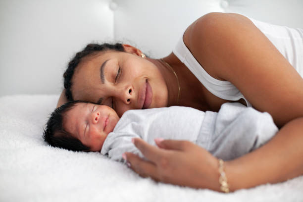 African-American mother having fun with cute baby boy on the bed stock photo