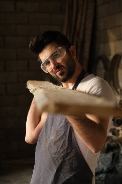 istock Manual worker blowing sawdust from a wood at carpentry workshop. 1443083861