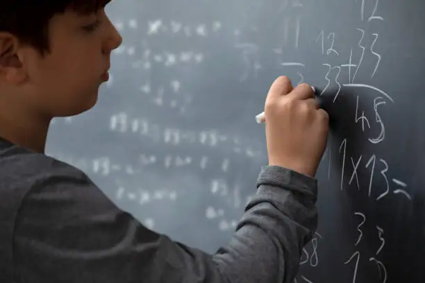 student kid writing to the blackboard at school