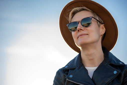30s blond woman with short hair in sunglasses, classy hat and leather jacket close up portrait