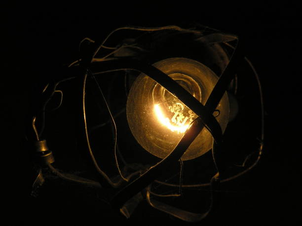 istock a light bulb glows in an old rusty lamp with a bent metal frame. 1443094320