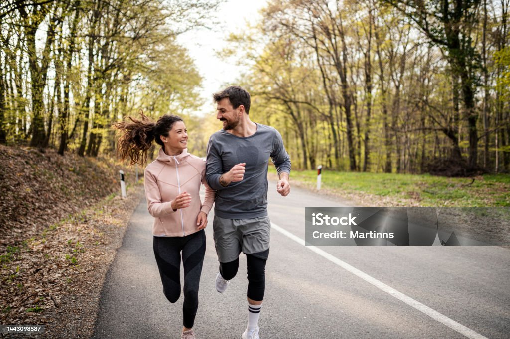 Happy athletic couple having fun while running in spring day Running Stock Photo