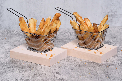 Baskets of French fries on wooden boards.