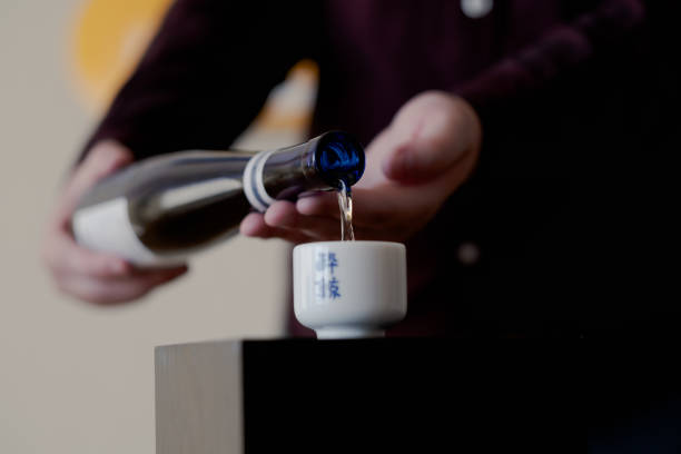 Sara demonstrates a sake pour Sara demonstrates a sake pour in Oakland. They are a sake sommelier, as well as a chef focused on Japanese and Korean cuisine. saki photos stock pictures, royalty-free photos & images