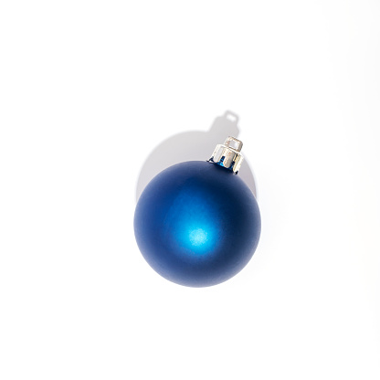 Blue Christmas ball on white background with sharp shadow. Top view.