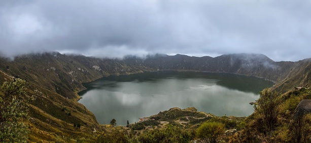 Quilotoa, Ecuador, October 20, 2022: Panoramic view of the water-filled crater lake and the most western volcano in the Ecuadorian Andes under thick clouds.