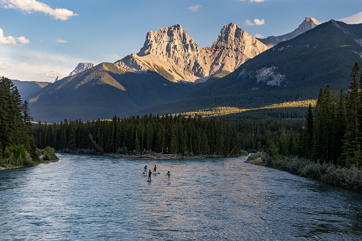Grupo de personas practicando paddle boarding en el río Bow con las montañas Three Sisters al fondo, Canmore, Alberta, Canadá. photo