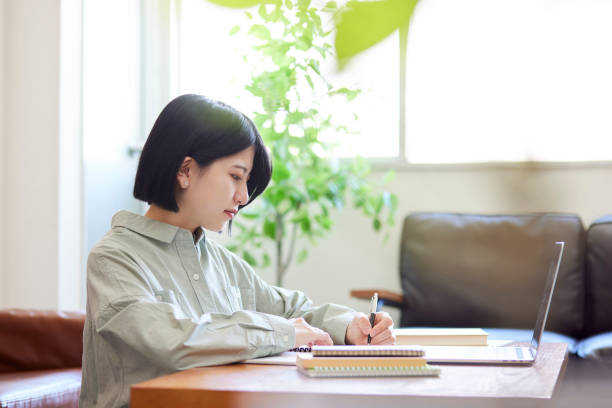 jeune femme japonaise étudiant en ligne dans le salon - living room learning healthy lifestyle one person photos et images de collection