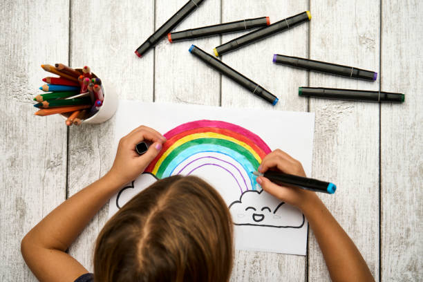 istock Little girl drawing rainbow at desk, csloe-up 1443126101
