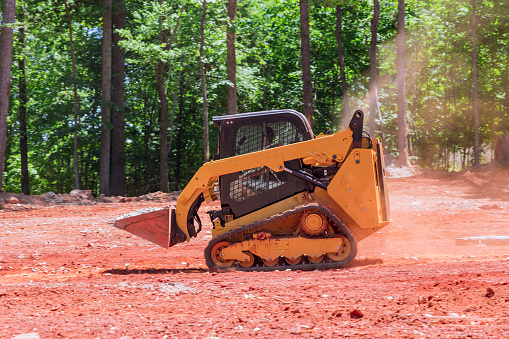 A bobcat with help of mini loader transports crushed stone to construction site