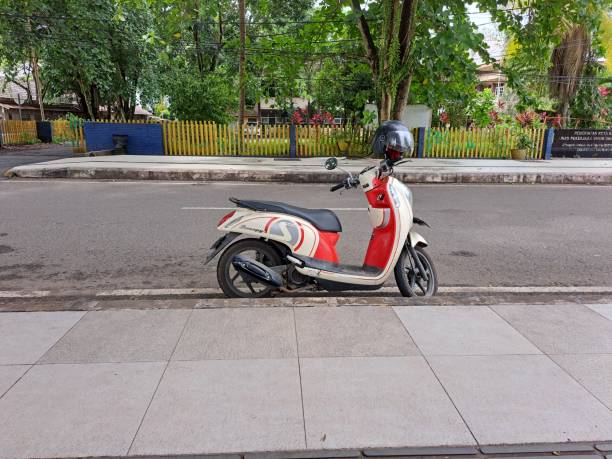 an automatic red-gray motorcycle parked on the side of the road stock photo