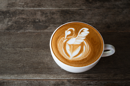 Latte art coffee with swan shape in coffee cup on wooden background, Hot drink