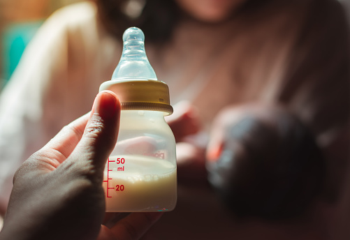 Father holding a baby bottle to give to his baby who is in his mother's arms