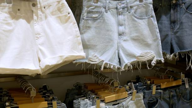 Stylish denim shorts on shelf store for youth and hipsters, sale shorts clothing store any color and different sizes. Short denim shorts accentuate woman's sexy curves. Comfortable clothes for summer pantalones cortos de mezclilla con estilo en la tienda de estantería para jóvenes y hipsters, venta de pantalones cortos de la tienda de ropa de cualquier color y diferentes tamaños. los pantalones cortos de mezclilla acentúan las curvas sexys de la mu