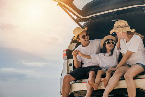 dad, mom and daughter enjoying road trip sitting on back car - family beach cheerful happiness imagens e fotografias de stock