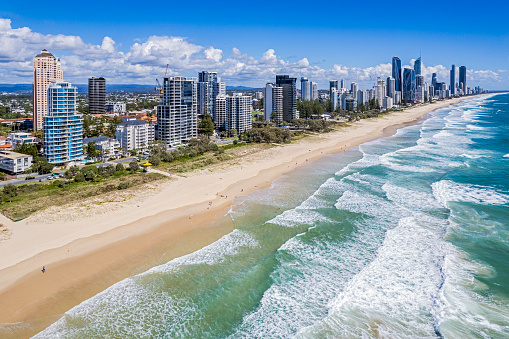Aerial View Broadbeach towers, Australia's Gold Coast looking north to Surfers Paradise from above the breaking waves. Surf lifesaver (lifeguard) towers with yellow canopies are visible along the sandy beach.