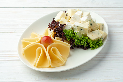 Assortment of cheese on a white plate on table