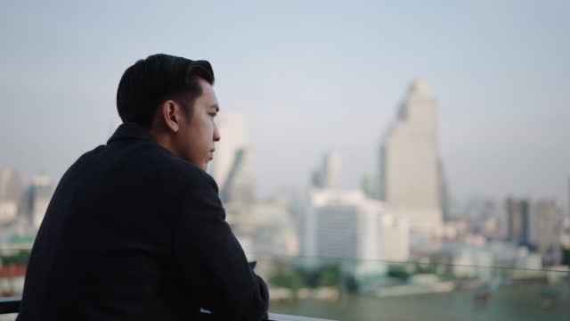Businessman standing on rooftop looking to city,