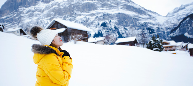 Grindelwald Switzerland top of Europe, Asian woman wearing yellow coat.She is feel Very happy on vacation in the mountains Background.travel trip  Snowy winter on Mount Grindelwald in Switzerland,