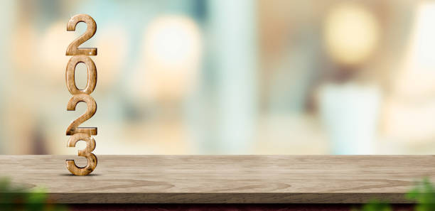 istock New year 2023 (3d rendering) on brown wood table at blur abstract bokeh light home background with blur leaf foreground,Mock up banner for display of product,holiday celebration greeting card 1443168749