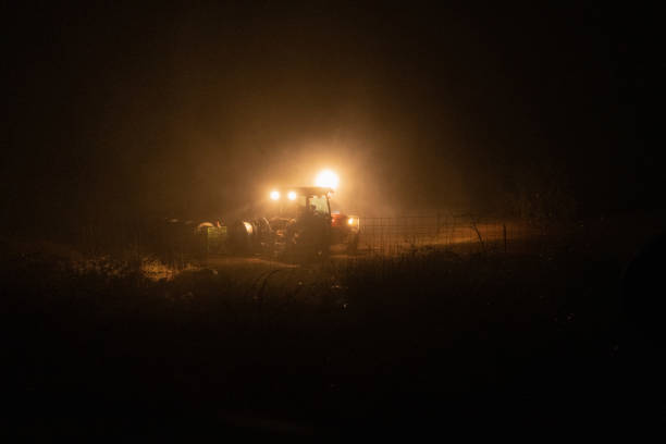 istock Street lamp and a tractor in a field during nighttime 1443170333