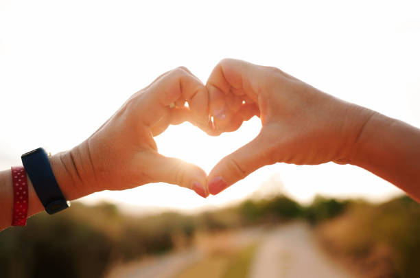 istock Hands formulating a heart on a blurred background of a sunset 1443171099