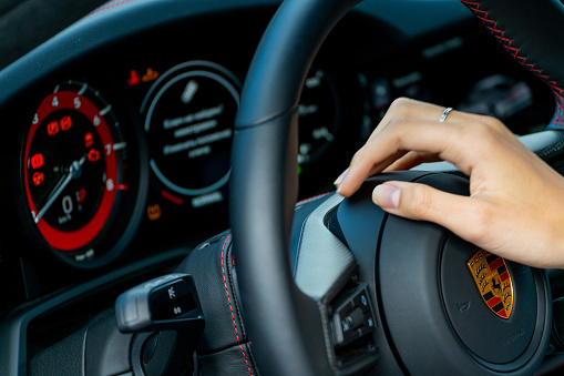 Moscow, Russia – August 13, 2021: A closeup of a female's hand on the steering wheel of the luxury modern Porsche car