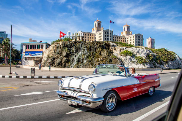 Classic luxury car through the streets of Havana with the Nacional Hotel def Cuba in the background Havana, Cuba – December 31, 2019: A classic luxury car through the streets of Havana with the Nacional Hotel def Cuba in the background def picture photos stock pictures, royalty-free photos & images