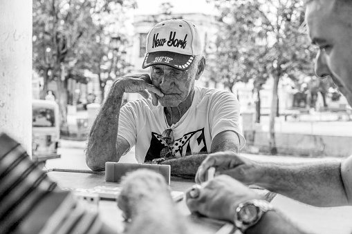 Habana, Cuba – October 25, 2019: A grayscale closeup of the older people sitting at the table outdoors. Havana, Cuba.