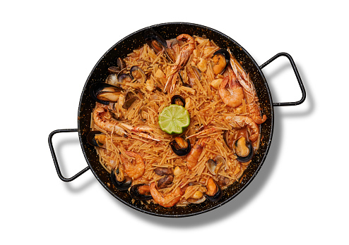 A top view of delicious Fideua with seafood in the pan on the white surface