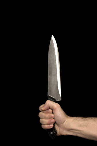 image of a hand holding a big knife in the dark
