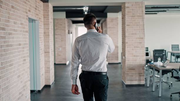 istock Caucasian man on a call while walking in a corridor. Pictured from the back. 1443176149