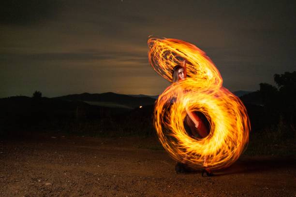 istock Female standing in a field with long exposure fire effects 1443180954