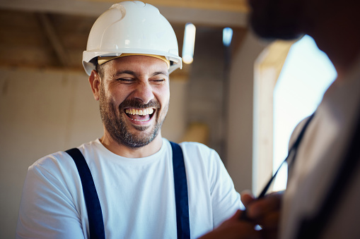 Cheerful worker having fun while laughing at construction site.