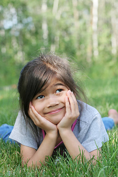 istock Little Girl Pondering while lying on grass 144318277