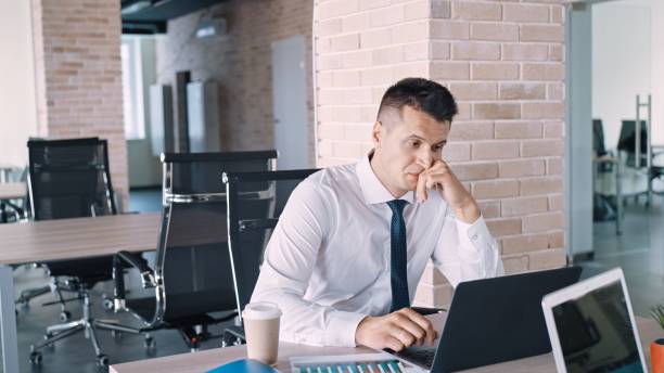 istock Thoughtful man in front of her laptop in an empty office staring at desktop 1443182957