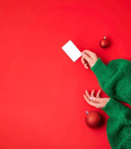 Christmas shopping concept. Flat lie hands in a green sweater with bonus card. Banner on a red background stock photo