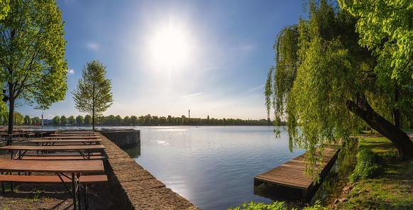 The beautiful Maschsee lake in Hannover with benches and lush trees on a sunny day