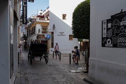 Cordo, Spain – April 30, 2022: A small beautiful street with people and a carriage in Cordoba city, Andalusia, Spain