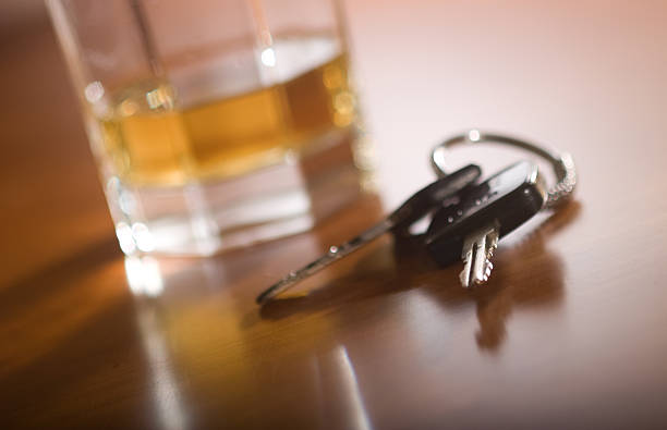 drink and drive A set of car keys in the foreground and a glass of whiskey behind. pics of drunk driving accidents stock pictures, royalty-free photos & images