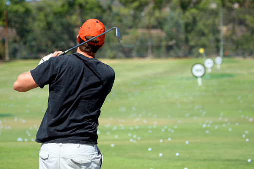 A man hitting golf balls at a driving range