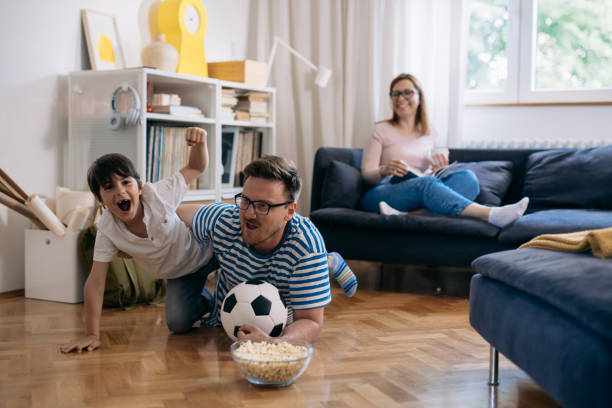 istock cheerful father and son watching soccer game at home 1443194730