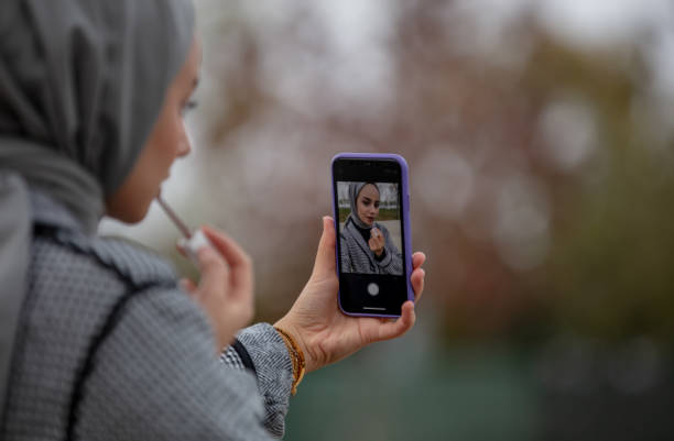 istock Young hijab girl is doing makeup in public park. 1443195428