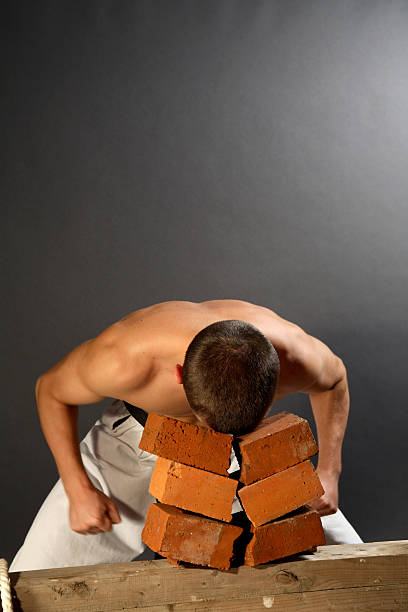 istock Young sporty karate man breaking three bricks on gray background 144319763