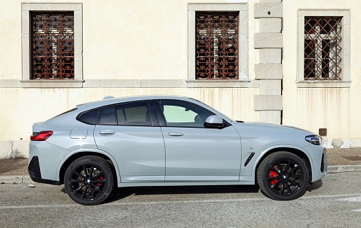 Udine, Italy. November 19, 2022.New gray Bmw x4 parked at the roadside in a city street. Side view.