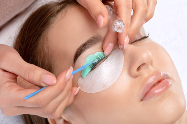 make-up artist makes the procedure of lamination and dyeing of eyelashes to a beautiful woman in a beauty salon. eyelash extensions. eyelashes close-up - oppakken stockfoto's en -beelden