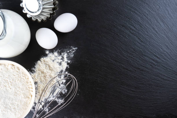 istock Baking ingredients flour, eggs, milk, bakeware on black slate background with copy space 1443201210