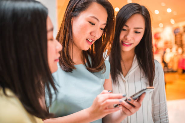 istock Good Looking Asian Friends Using a Phone while Standing at a Mall 1443203094